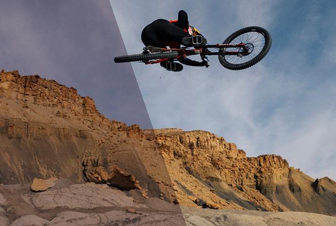 A person riding a bike up in the air over the mountains.