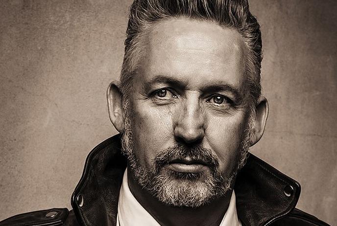 A headshot of Harland Williams looking at the camera with a blank expression.