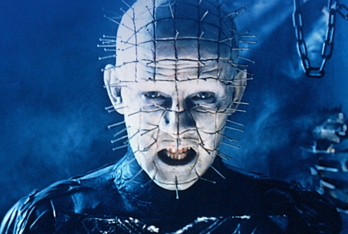 A dark, eerie movie poster for “Hellraiser” featuring a sinister figure with pins in its head, glowing eyes.