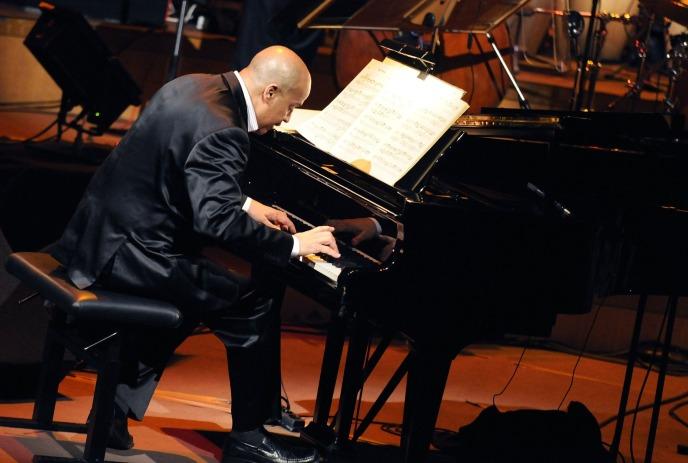 Hilario Durán performing piano on stage, wearing a suit.