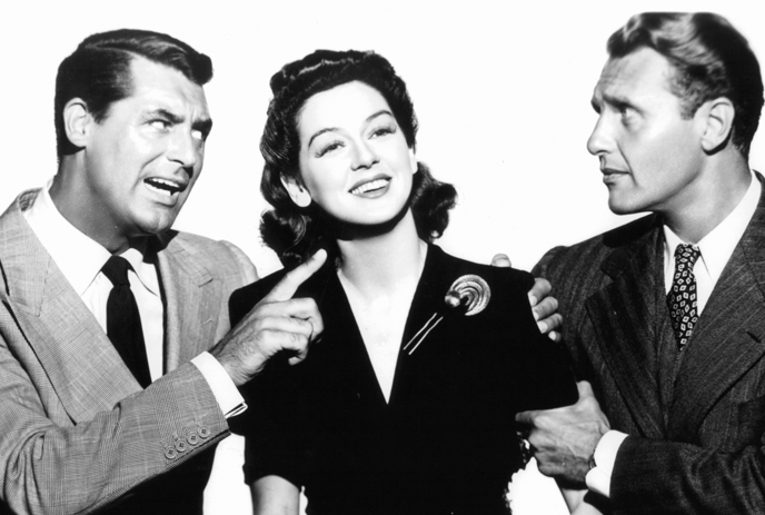 Three formal figures in black-and-white, talking and smiling, one points, it is a film scene.