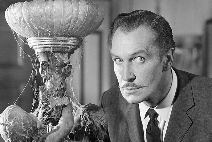 A black and white photo shows a man with a pencil mustache and serious expression, standing next to a cobweb-covered ornate.