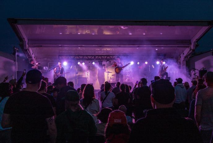 A band performs under purple lights on an outdoor stage at a previous PondFest.