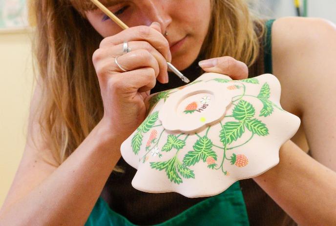 A young girl working on a ceramic pot.