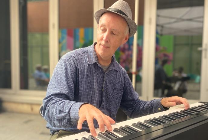 Person wearing a hat, playing a keyboard.