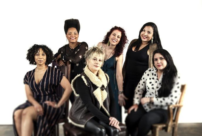 Jane Bunnett with Maqueque, a group of six women posed together against a white background.