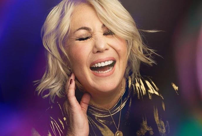 Jann Arden laughing, wearing a gold dress.