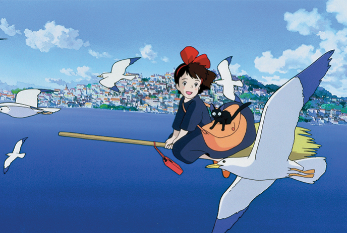 An animated scene: a character on a broomstick flies with a large white bird over a coastal town.