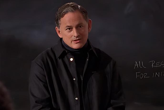 Victor Garber standing against a black background.