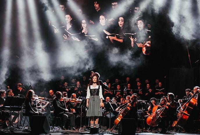 Person in front of a full orchestra on stage.