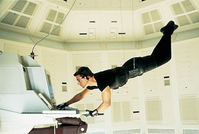 Person in black using a computer while floating mid-air in a white room.