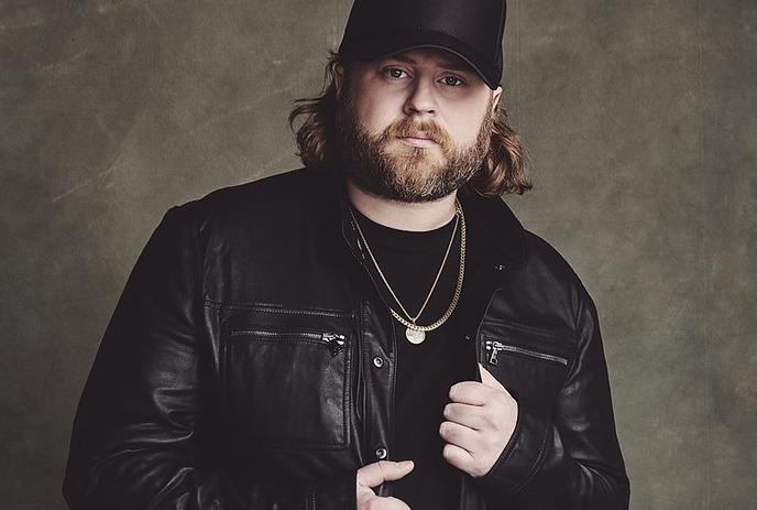 Nate Smith posing for the camera in front of a brown background.