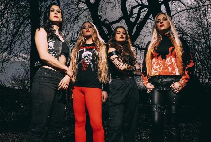 The 4 band members of Nervosa posing in front of a dark forest.