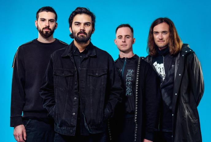 The 4 band members of Northlane, posing for the camera in front of a blue background.