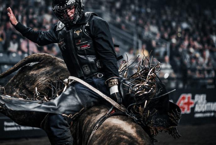 A person riding a bull at a rodeo event.