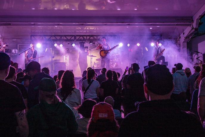 A band performs under purple lights on an outdoor stage at a previous PondFest.