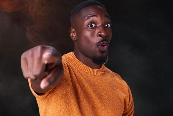 Preacher Lawson holding a microphone on stage in front of a blue curtain.