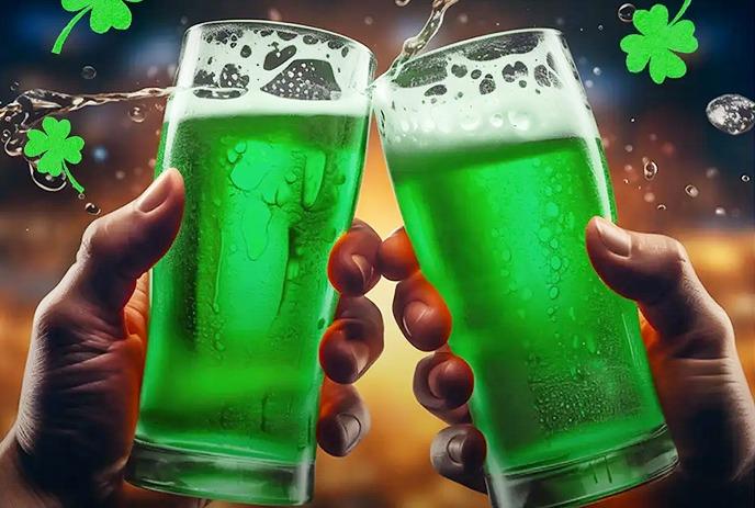 Two hands holding glasses of green beer clink together, with shamrocks and bubbles in the background.