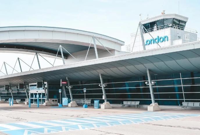 An Exterior view of London Ontario’s YXU airport showcasing its curved entrance canopy and control tower labeled 'London'.