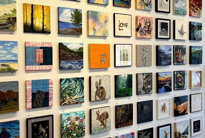 A wall filled with small, colourful paintings showcasing various styles.