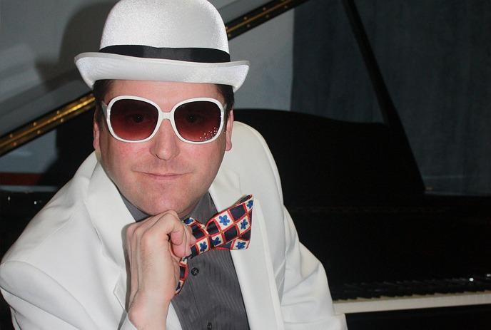 Close-up image of Elton John tribute actor wearing a white hat and white sunglasses.