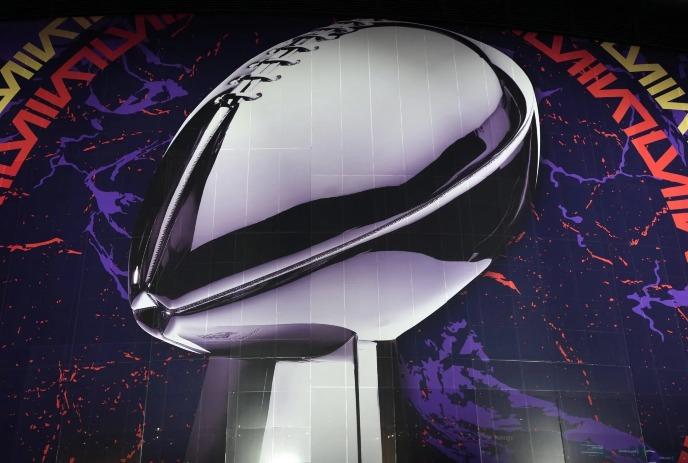 A large, shiny silver football trophy displayed against a dark background.