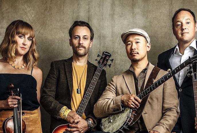 The 4 band members of The Fugitives, posing with their instruments in front of a brown background.