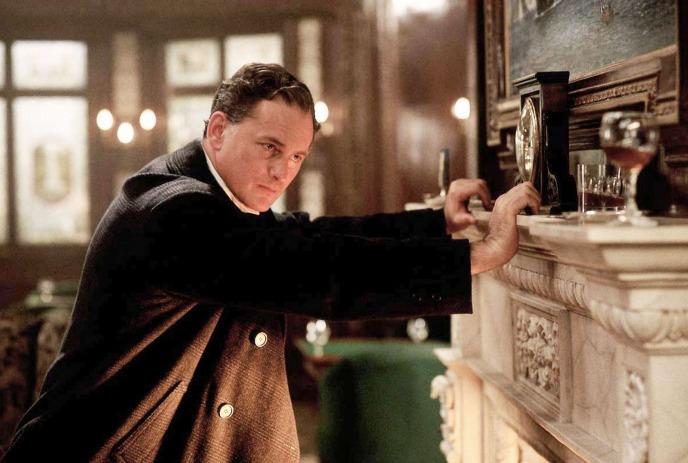 Victor Garber leaning on a fireplace in the movie Titanic.