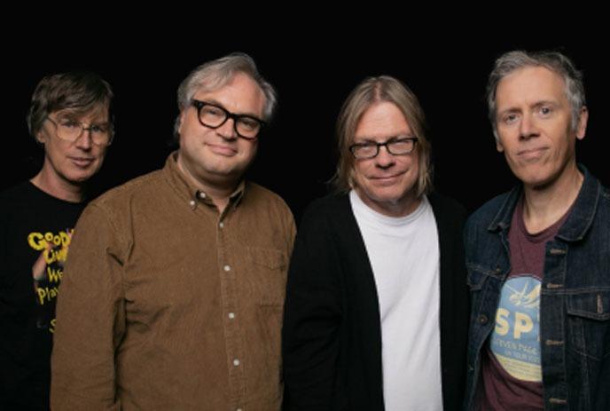 The 4 band members of the Trans-Canada Highwaymen, standing in front of a black background.