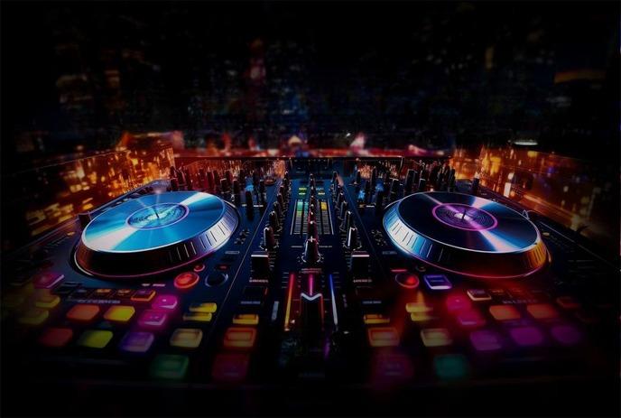 An image of a DJ mixing board at night with vibrant, illuminated buttons and sliders.