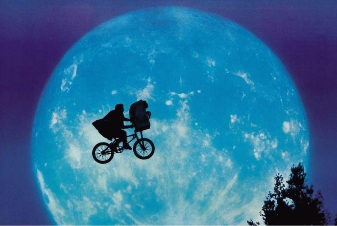 Silhouette of a person on a bike against a full moon, evoking nostalgia and a sense of adventure.