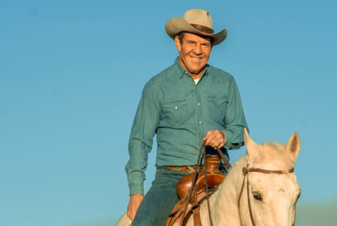 Dennis Quaid as Ronald Reagan riding a white horse with bule sky in the background.