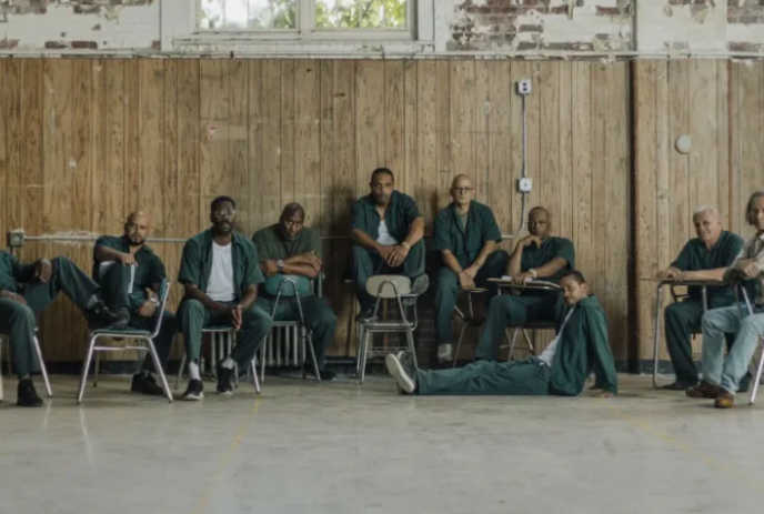 Group of inmates sitting together in front of a wood panel wall.