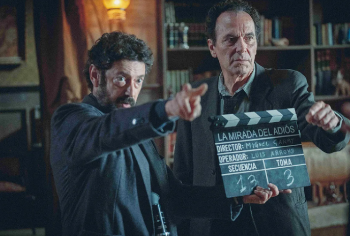 Two people standing with a clapboard, directing actors.