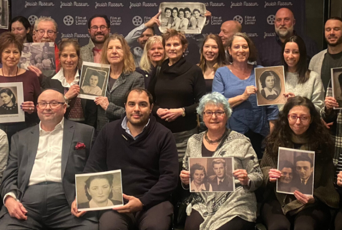 Group of people holding black and white photos of loved ones.