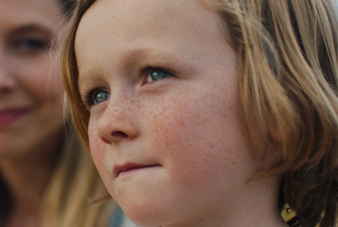 Young person looking ahead, with an adult behind them.