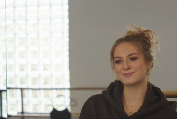 Person sitting in a ballet studio looking at the camera.