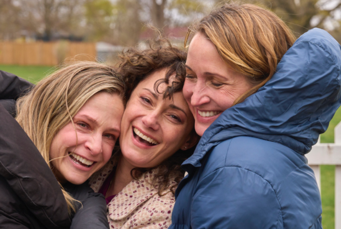 Three people standing together and smiling at the camera.