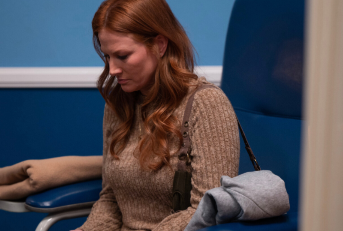 Person sitting on a blue chair, looking pensive.