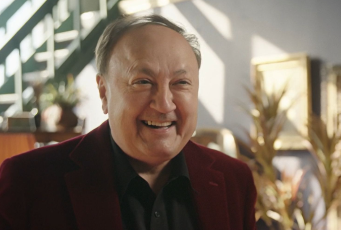 Person wearing a burgundy sport coat, smiling at the camera.