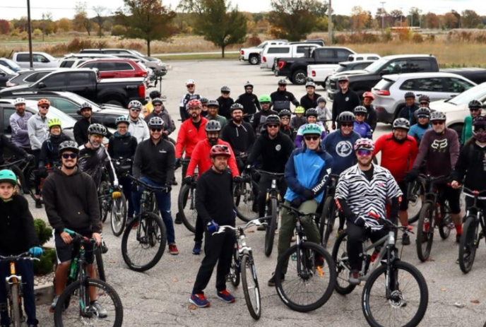 Group of cyclists gathered together in a parking lot.