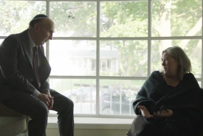 Two people sitting in a front room talking together.