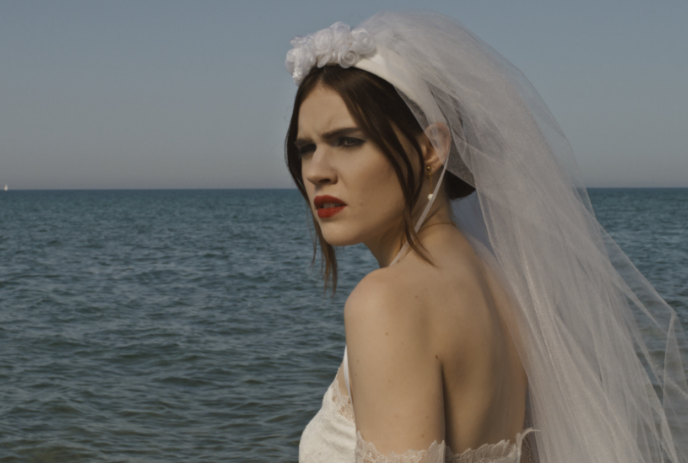 A bride standing in front of a body of water looking confused.