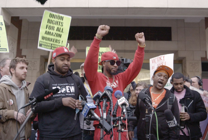 Group of workers standing together at some news microphones.