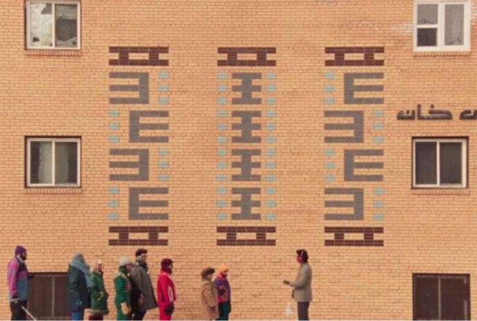 People standing in front of a building listening to another person speaking.