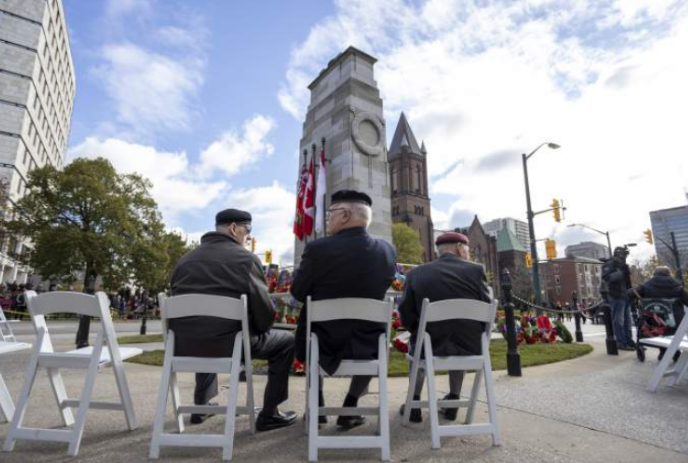 Group of Veterans sitting together around the Cenotaph.