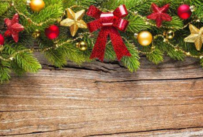 Evergreen boughs with stars and hanging glass ornaments on a wooden background.