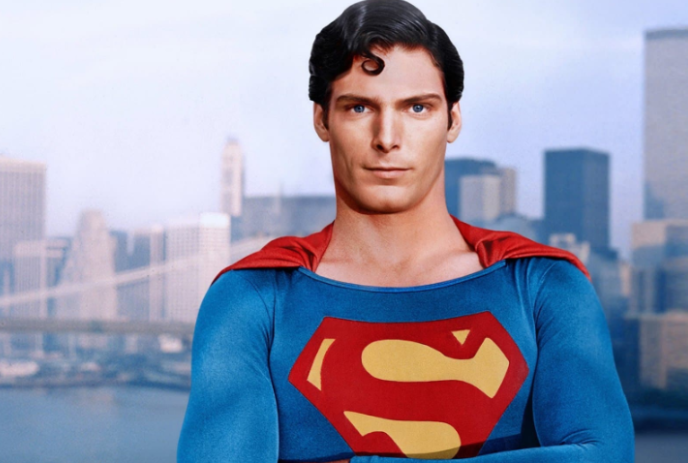 Superman wearing his cape, standing in front of a city.