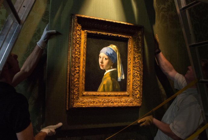 Two workers hanging the Girl with a Pearl Earring painting.