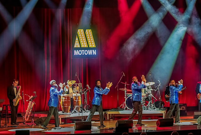 Group of singers on stage with their instruments, entertaining a crowd.